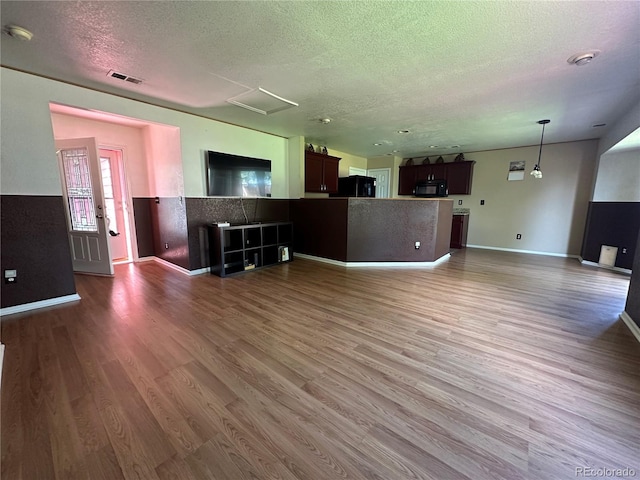 unfurnished living room featuring wood-type flooring and a textured ceiling