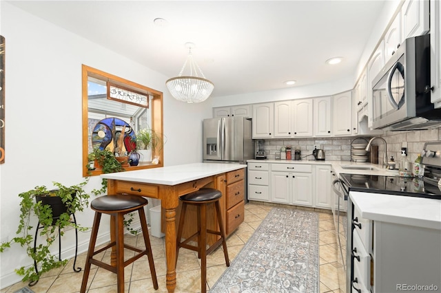 kitchen featuring an inviting chandelier, sink, appliances with stainless steel finishes, a kitchen island, and a kitchen bar