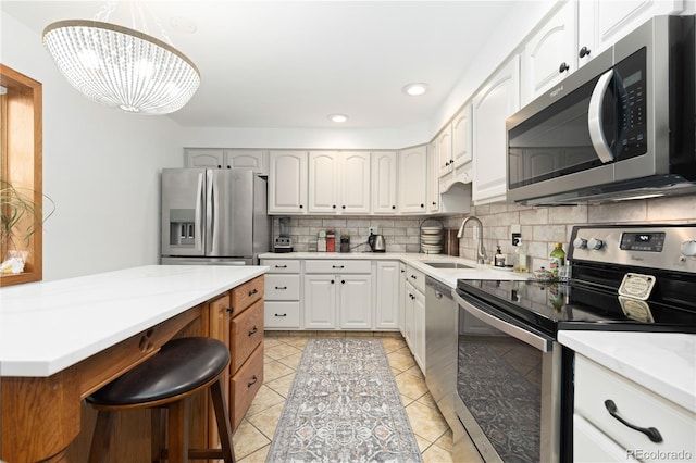 kitchen with white cabinetry, sink, hanging light fixtures, an inviting chandelier, and appliances with stainless steel finishes