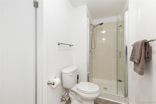 bathroom featuring toilet and a shower with shower door