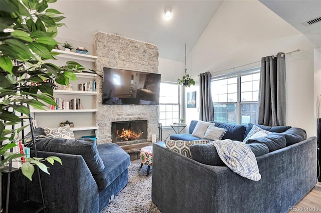 living area with a fireplace, wood finished floors, and high vaulted ceiling