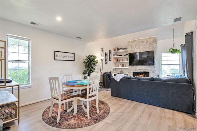 dining space with light wood-style flooring, a fireplace, and baseboards