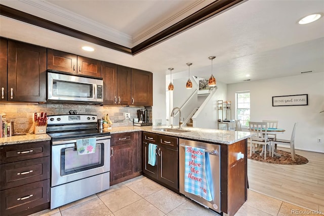 kitchen with appliances with stainless steel finishes, a sink, ornamental molding, a peninsula, and decorative backsplash