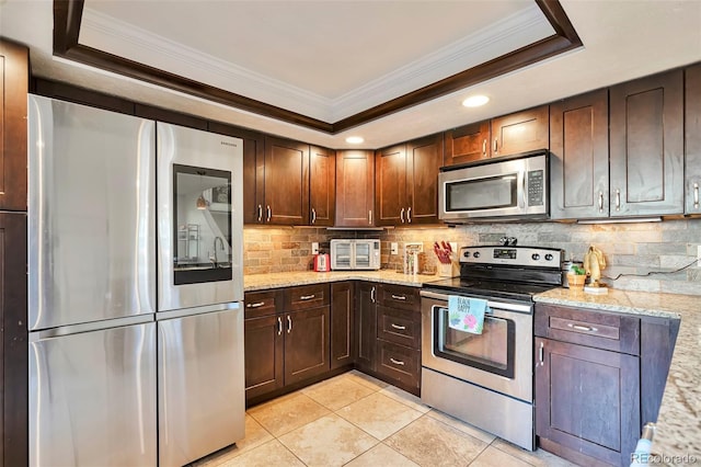 kitchen featuring stainless steel appliances, ornamental molding, a tray ceiling, backsplash, and light tile patterned floors