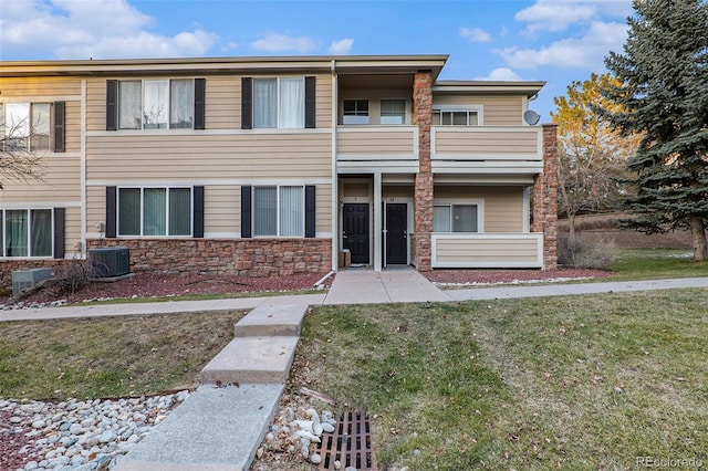 view of property featuring a balcony, a front yard, and central AC