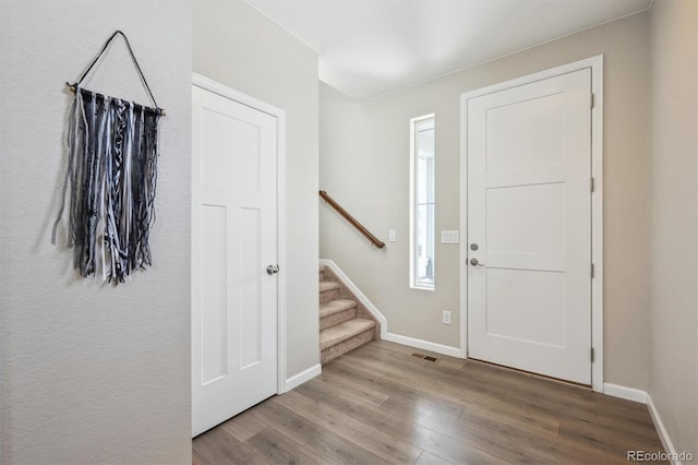 entryway featuring baseboards, stairs, wood finished floors, and visible vents