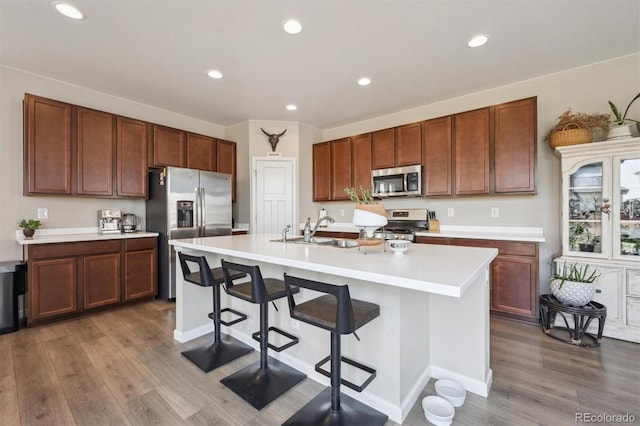kitchen featuring a sink, appliances with stainless steel finishes, wood finished floors, and light countertops