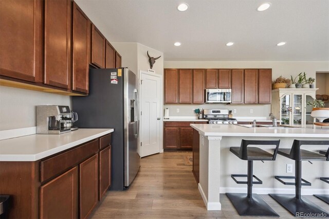 27837 E 8th Ave, Aurora, CO 80018 - kitchen with a kitchen breakfast bar, appliances with stainless steel finishes, wood finished floors, a sink, and recessed lighting