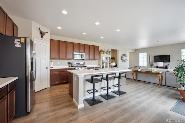kitchen with a breakfast bar area, light countertops, light wood finished floors, stainless steel appliances, and recessed lighting