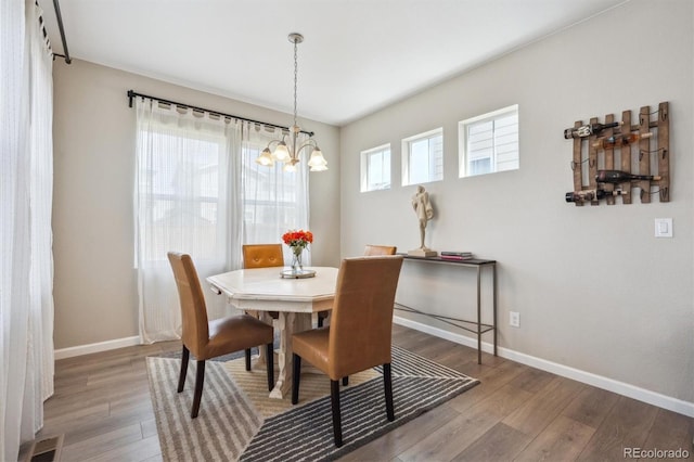 dining area featuring an inviting chandelier, baseboards, wood finished floors, and visible vents
