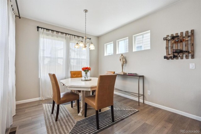 27837 E 8th Ave, Aurora, CO 80018 - dining area featuring an inviting chandelier, baseboards, wood finished floors, and visible vents