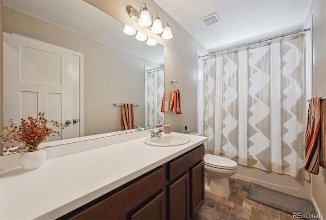 bathroom featuring visible vents, vanity, toilet, a shower with shower curtain, and stone finish floor