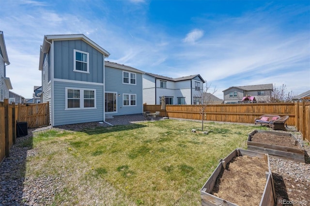 back of house with board and batten siding, a lawn, a garden, and a fenced backyard