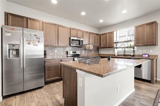 6484 N Ceylon Ct, Denver, CO 80249 - kitchen featuring stainless steel appliances, light wood-type flooring, a sink, light stone counters, and recessed lighting