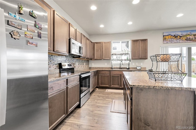 6484 N Ceylon Ct, Denver, CO 80249 - kitchen featuring stainless steel appliances, recessed lighting, light wood-style flooring, light stone countertops, and a kitchen island
