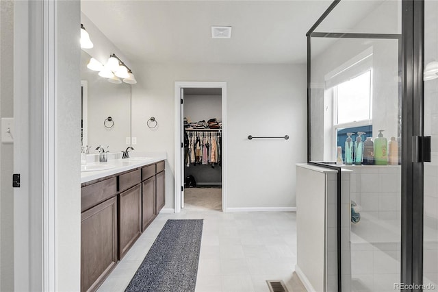 6484 N Ceylon Ct, Denver, CO 80249 - bathroom with double vanity, a walk in closet, a shower stall, tile patterned floors, and baseboards