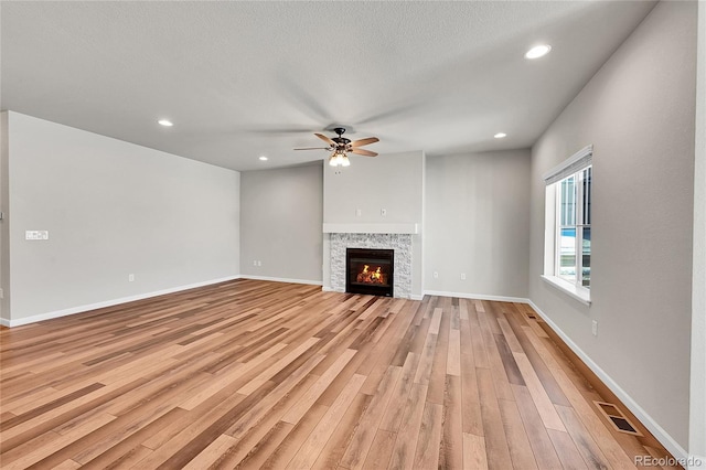 unfurnished living room with ceiling fan, light hardwood / wood-style flooring, and a textured ceiling