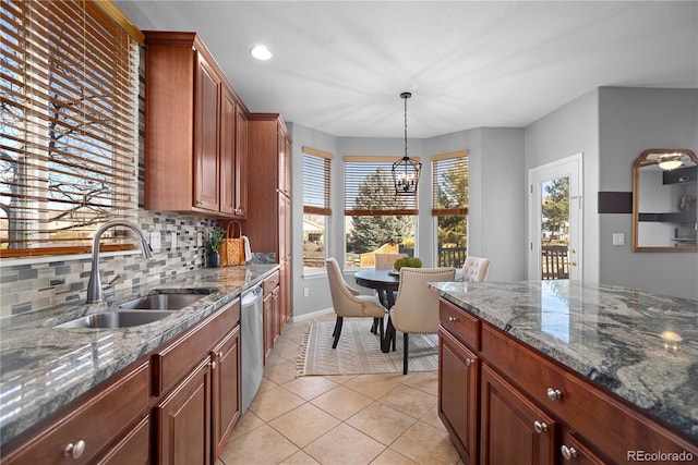 kitchen featuring sink, decorative light fixtures, light tile patterned floors, stainless steel dishwasher, and dark stone counters