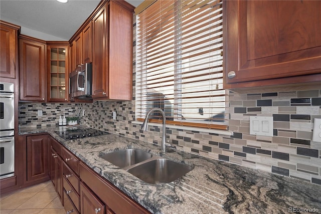 kitchen featuring sink, dark stone countertops, tasteful backsplash, black electric stovetop, and light tile patterned flooring