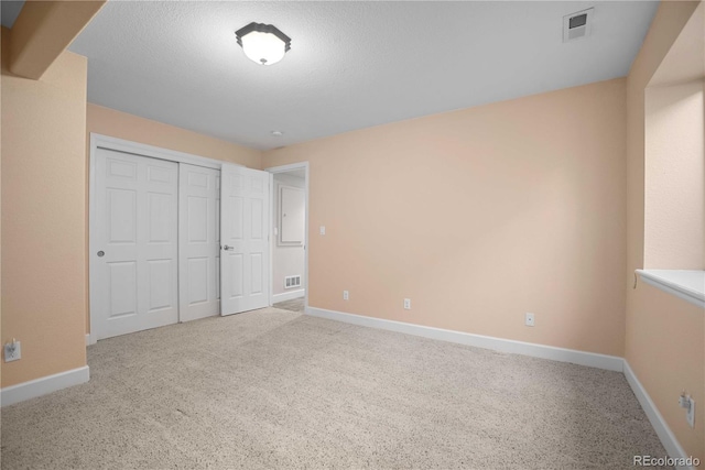 unfurnished bedroom featuring light colored carpet, a textured ceiling, and a closet