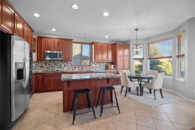 kitchen with sink, decorative light fixtures, a center island, dark stone countertops, and stainless steel appliances