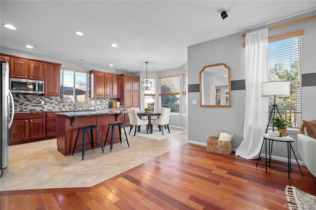 kitchen featuring pendant lighting, a breakfast bar area, tasteful backsplash, light hardwood / wood-style floors, and a kitchen island