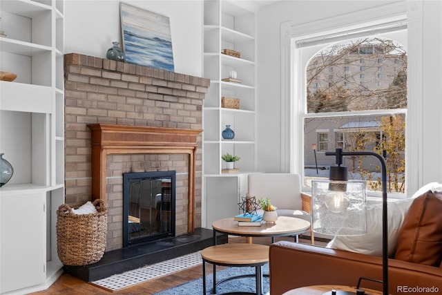 living area with hardwood / wood-style flooring, a brick fireplace, and built in features