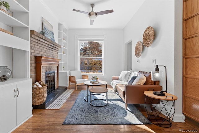 living room featuring dark hardwood / wood-style flooring, built in shelves, a fireplace, and ceiling fan