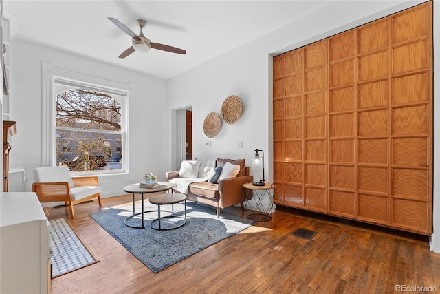 living room featuring ceiling fan and dark hardwood / wood-style flooring