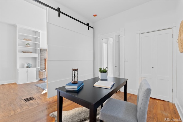 home office with a barn door and light wood-type flooring