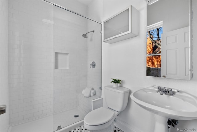 bathroom with tiled shower, toilet, and sink