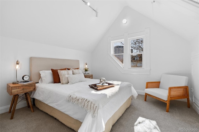 bedroom with vaulted ceiling, rail lighting, and light colored carpet