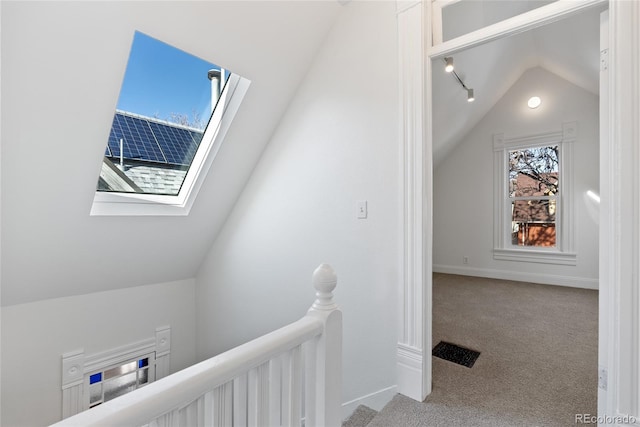 corridor featuring vaulted ceiling with skylight and carpet flooring