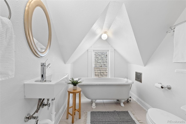 bathroom with lofted ceiling, toilet, a bathtub, and a textured ceiling