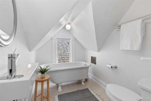 bathroom featuring a tub, lofted ceiling, a textured ceiling, and toilet