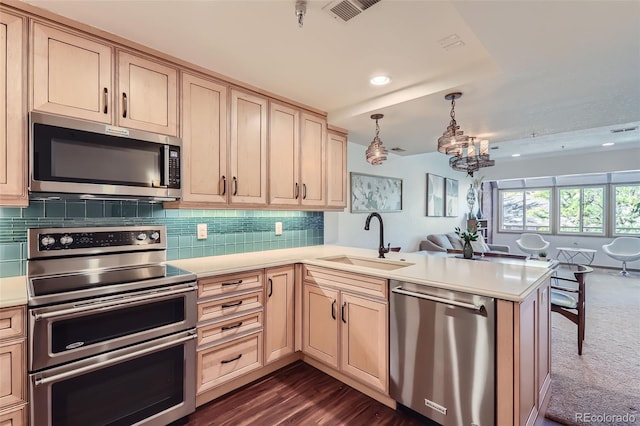 kitchen with sink, decorative light fixtures, appliances with stainless steel finishes, kitchen peninsula, and backsplash