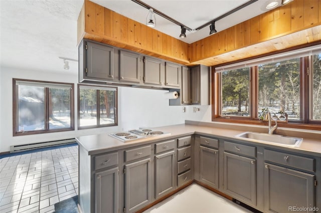 kitchen featuring sink, rail lighting, baseboard heating, white gas stovetop, and kitchen peninsula