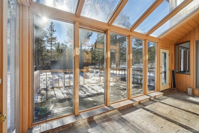 unfurnished sunroom with vaulted ceiling with skylight