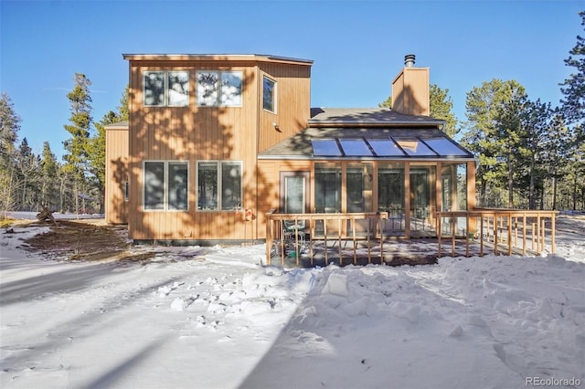 snow covered property featuring a sunroom and a deck