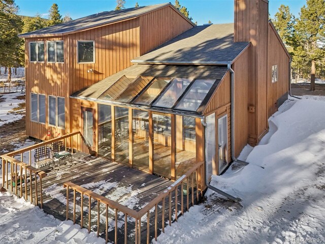 snow covered house featuring a sunroom