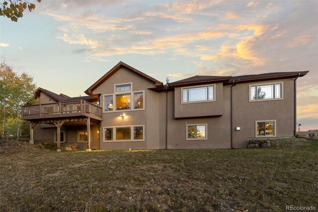 13909 Stone Chimney Ln, Pine, CO 80470 - back of property at dusk featuring a wooden deck, a lawn, and stucco siding