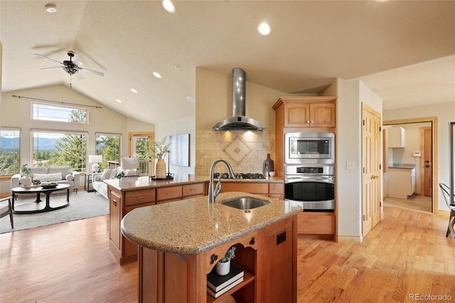 13909 Stone Chimney Ln, Pine, CO 80470 - kitchen featuring stainless steel appliances, wall chimney range hood, a kitchen island with sink, open floor plan, and lofted ceiling