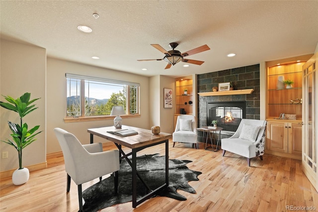 13909 Stone Chimney Ln, Pine, CO 80470 - office space featuring light wood finished floors, a fireplace, a textured ceiling, recessed lighting, and a ceiling fan