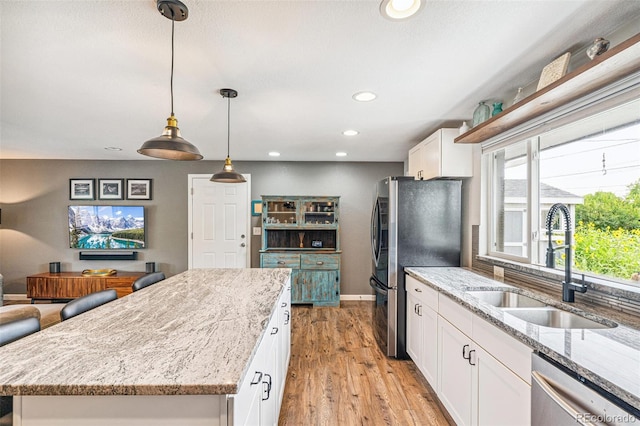 6066 Simms St, Arvada, CO 80004 - kitchen featuring appliances with stainless steel finishes, white cabinets, light stone countertops, a center island, and recessed lighting