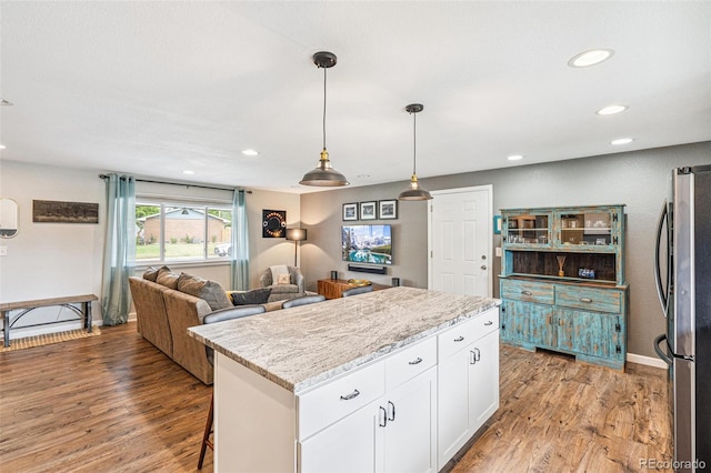 6066 Simms St, Arvada, CO 80004 - kitchen with freestanding refrigerator, white cabinetry, light wood finished floors, recessed lighting, and a center island