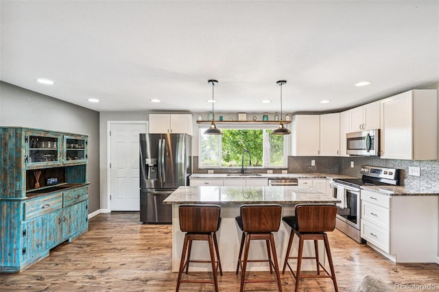 6066 Simms St, Arvada, CO 80004 - kitchen featuring stainless steel appliances, light stone countertops, white cabinets, tasteful backsplash, and recessed lighting
