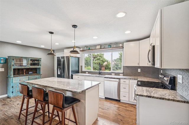 6066 Simms St, Arvada, CO 80004 - kitchen featuring appliances with stainless steel finishes, a breakfast bar area, light wood-style floors, decorative backsplash, and light stone counters