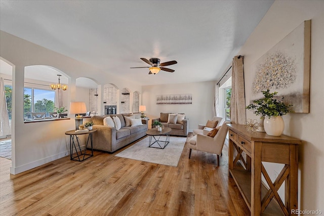 18263 E Mansfield Ave, Aurora, CO 80013 - living area featuring arched walkways, ceiling fan, light wood-style flooring, a chandelier, and baseboards