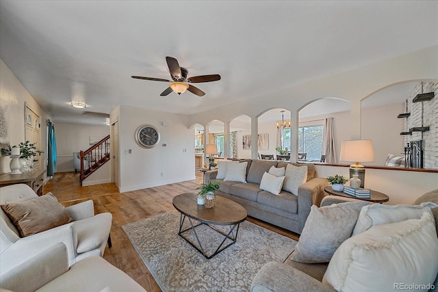 18263 E Mansfield Ave, Aurora, CO 80013 - living room featuring arched walkways, wood finished floors, stairs, a ceiling fan, and a chandelier