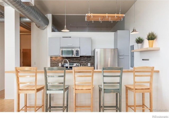3100 Huron St Unit 3P, Denver, CO 80202 - kitchen featuring appliances with stainless steel finishes, decorative backsplash, a breakfast bar, and pendant lighting